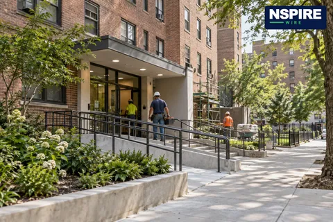 Editorial illustration of an apartment entrance and accessible ramp in a brick housing campus. Not a photograph of Nostrand Houses.