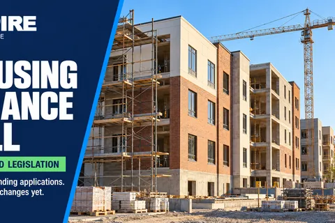 Affordable apartment buildings under construction with a crane, illustrating a House bill to streamline state housing finance.